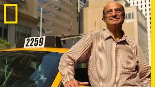 A man stands next to a yellow taxi and smiles